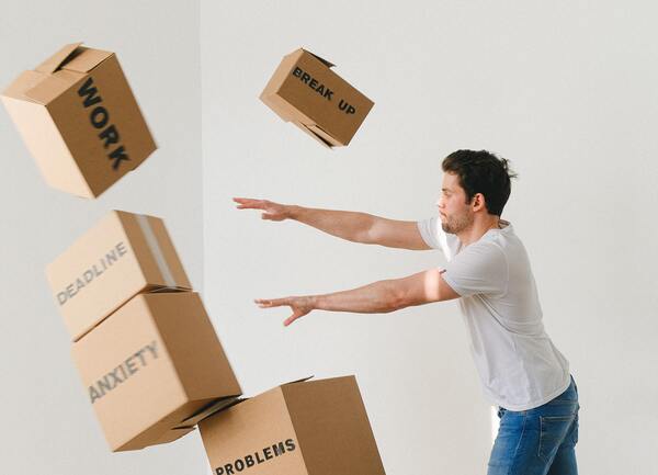 Joven arrojando cajas con títulos impresos en ellas. La que más destaca es la que dice empleo.